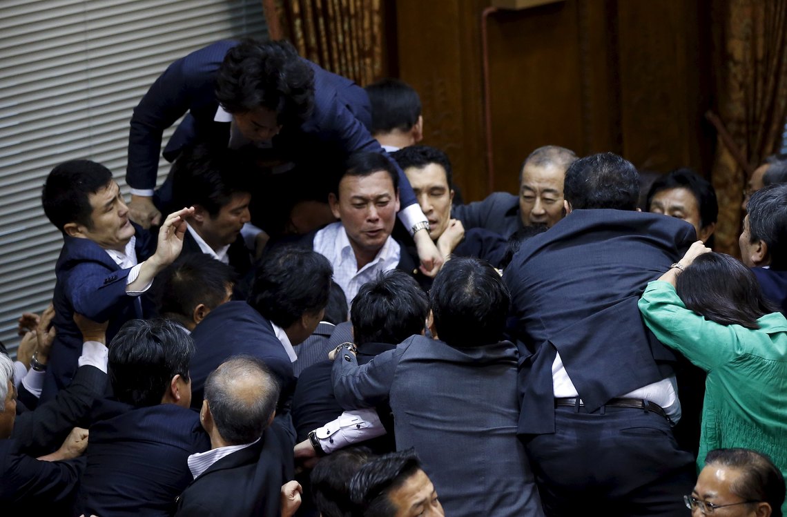 Opposition Democratic Party of Japan lawmaker Hiroyuki Konishi (top) climbs over other lawmakers who are guarding Yoshitada Konoike, chairman of the upper house special committee on security, before a vote at an upper house special committee session on security-related legislation at the parliament in Tokyo, Japan, September 17, 2015. REUTERS/Toru Hanai